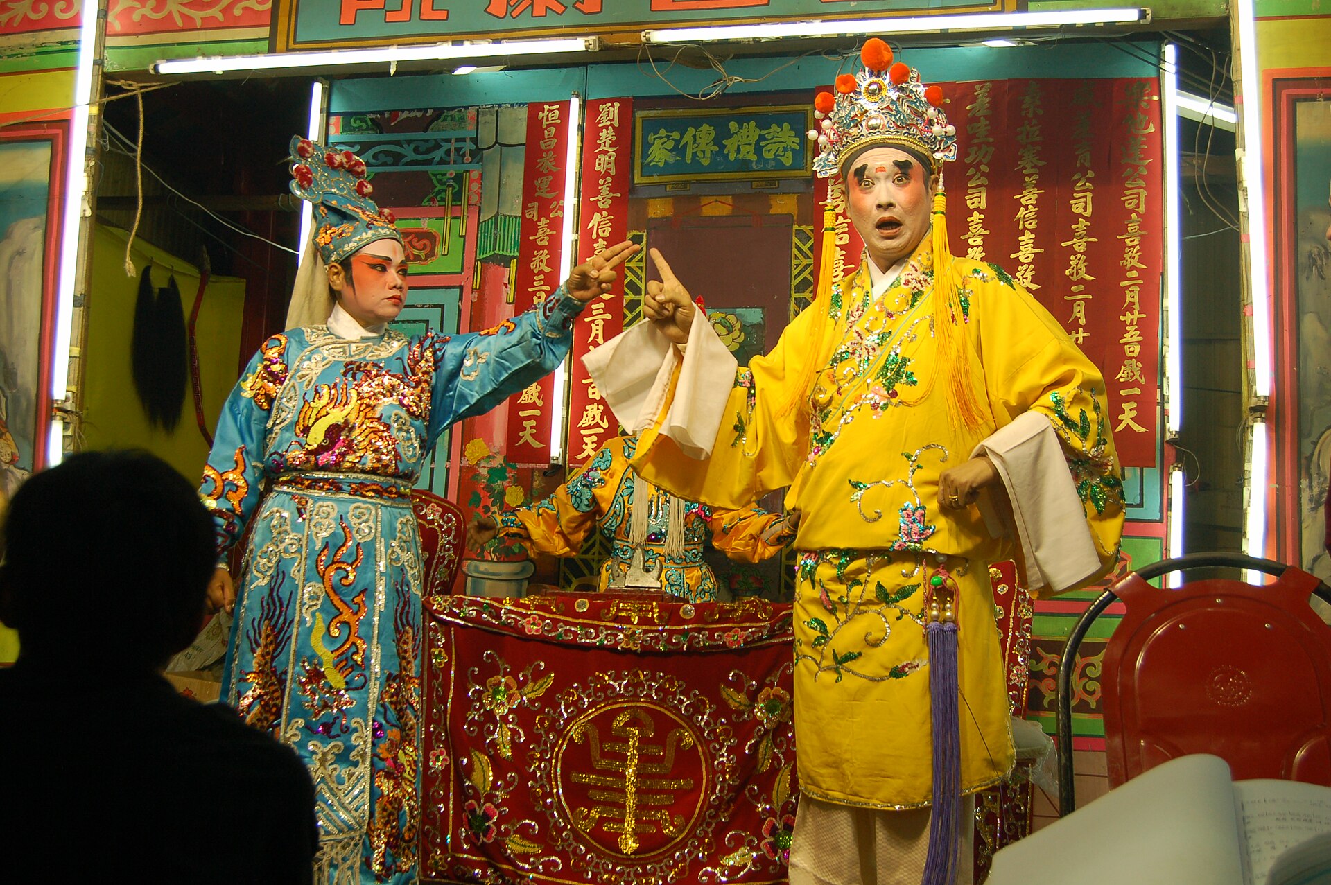 A Teochew opera performer in full makeup and golden headdress, a close and intense stage portrait